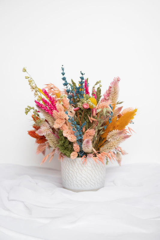 Arreglo floral en jarrón verde – tonos azules y mostazas